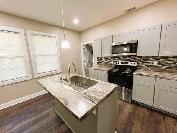 a kitchen with stainless steel appliances granite countertop a stove refrigerator sink and microwave
