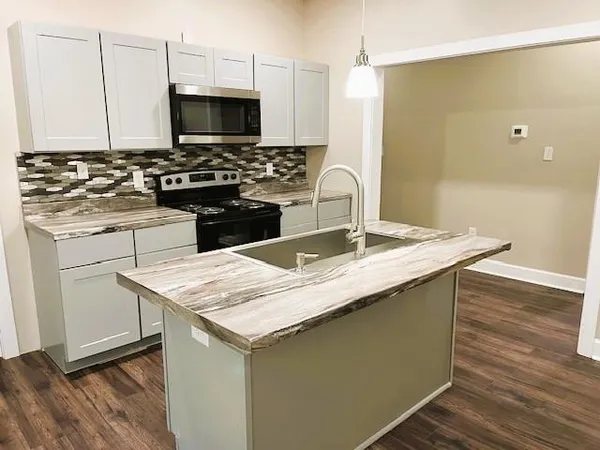 a kitchen with a sink a microwave a stove and cabinets