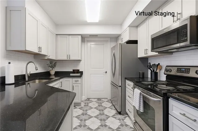 a kitchen with stainless steel appliances granite countertop a stove a sink and a microwave