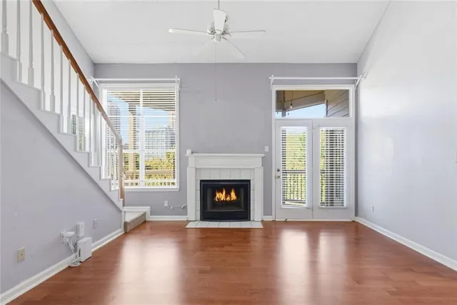 a view of an empty room with wooden floor fireplace and a window