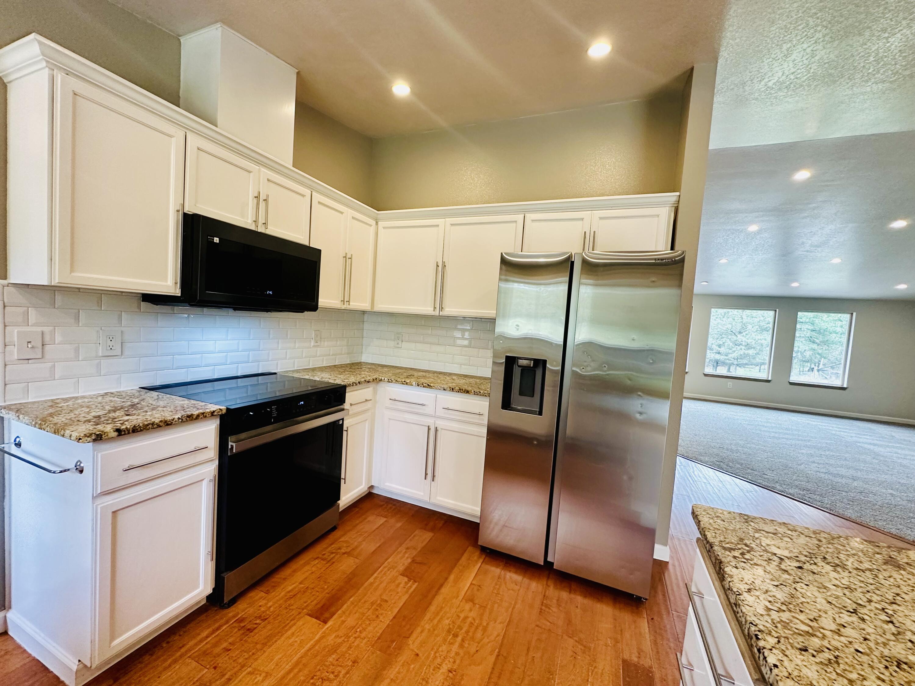 16524 Fieldcrest Road Klamath Falls, OR 97603 - Photo 18 of 58 a kitchen with granite countertop a refrigerator a sink a stove a microwave and wooden floor