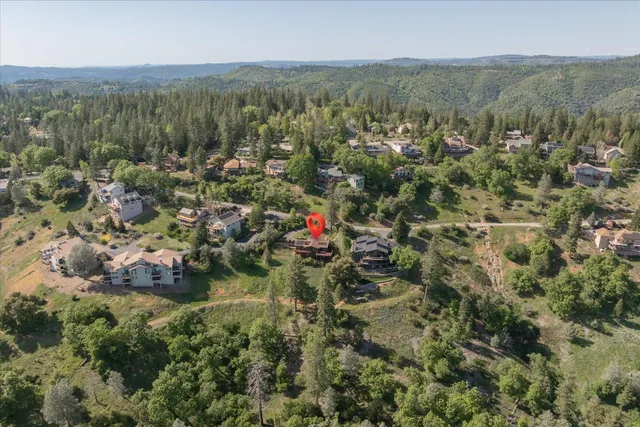 an aerial view of residential house with parking and trees