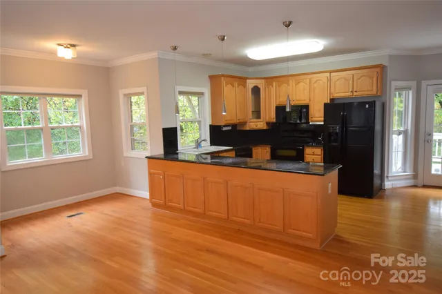 a kitchen with stainless steel appliances granite countertop a refrigerator a stove top oven and a large window