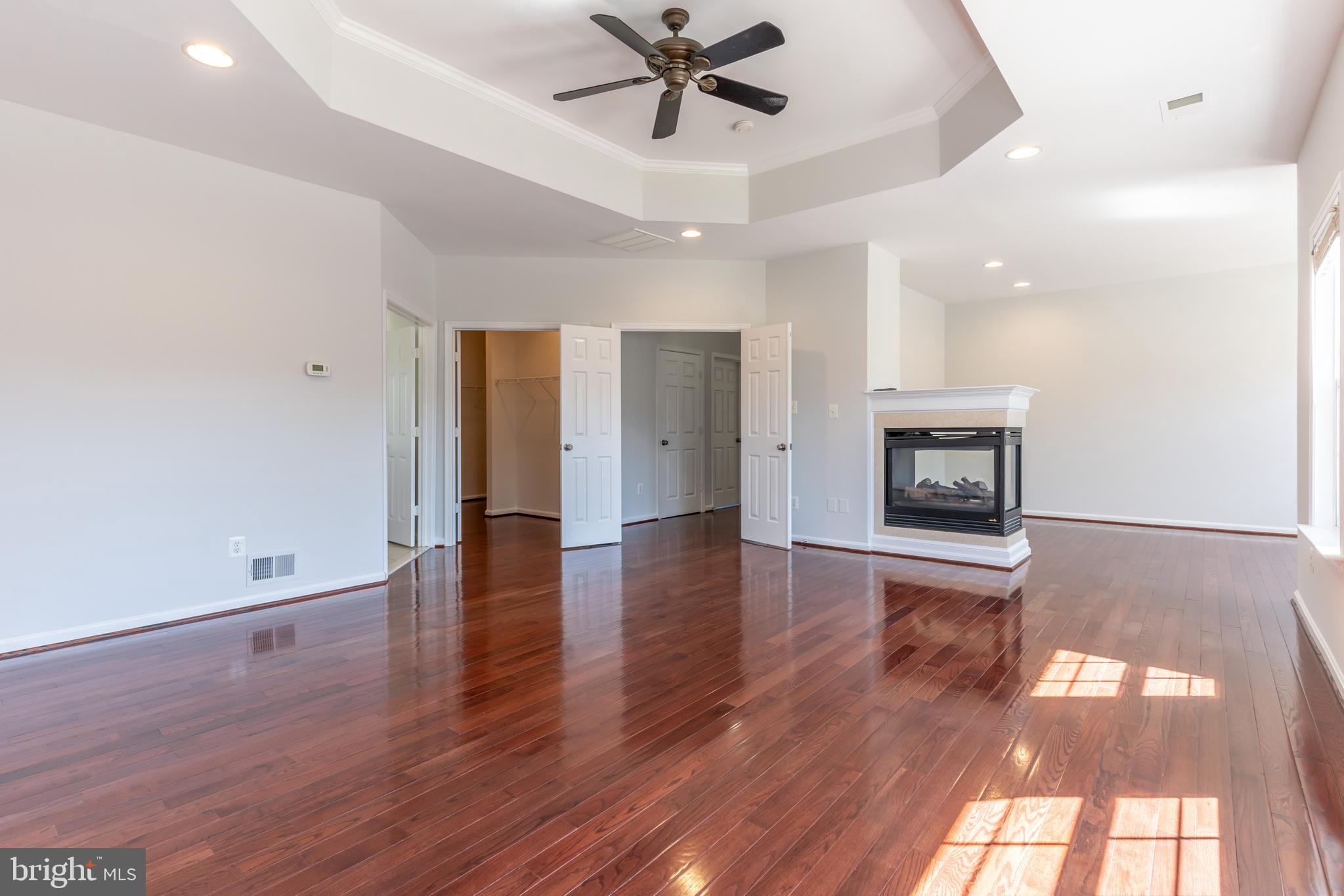 12675 Rushing Creek Court Bristow, VA 20136 - Photo 22 of 49 an empty room with wooden floor a fireplace and windows