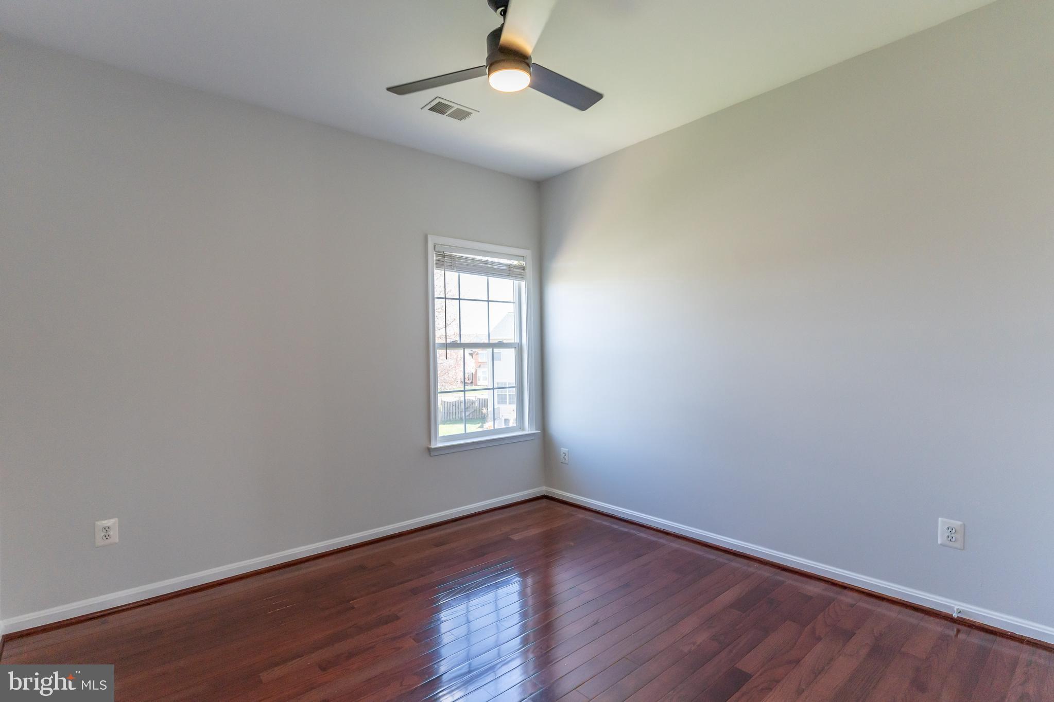 12675 Rushing Creek Court Bristow, VA 20136 - Photo 7 of 49 an empty room with wooden floor chandelier fan and windows