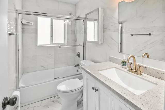 a bathroom with a granite countertop sink a toilet and shower