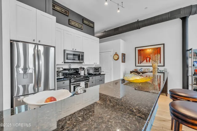 a kitchen with stainless steel appliances granite countertop a refrigerator a stove and a sink with wooden floor