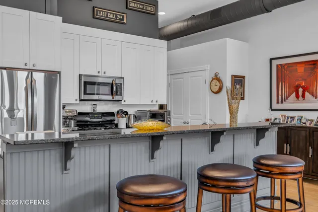 a kitchen with stainless steel appliances kitchen island a table chairs in it and wooden floors