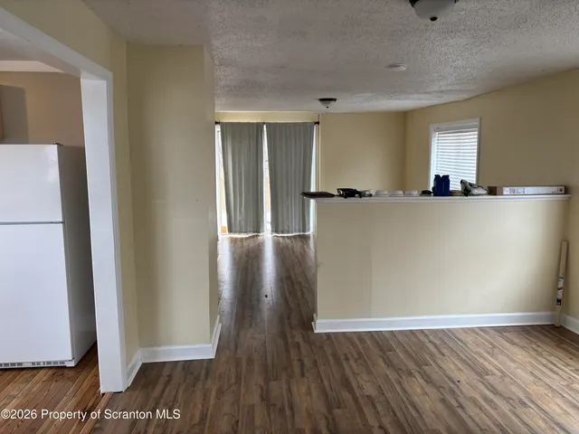 a view of a room with wooden floor and a refrigerator