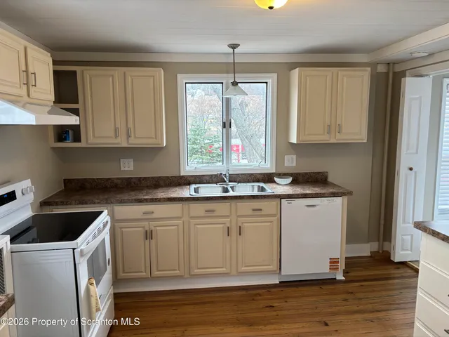 a kitchen with granite countertop a sink cabinets and wooden floor