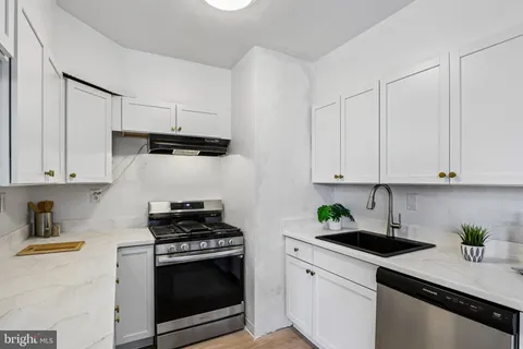 a kitchen with granite countertop a sink a stove and cabinets