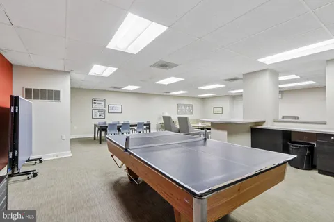 a dining hall with stainless steel appliances kitchen island a table and chairs in it
