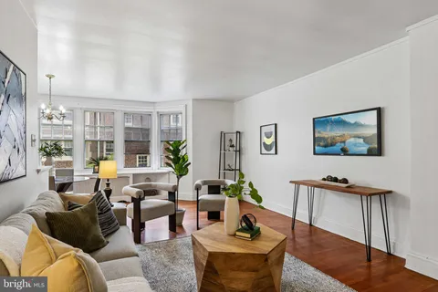 a living room with furniture a lamp wooden floor and a large window