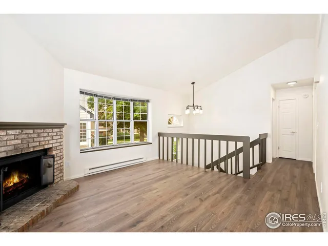 a view of an empty room with wooden floor fireplace and a window