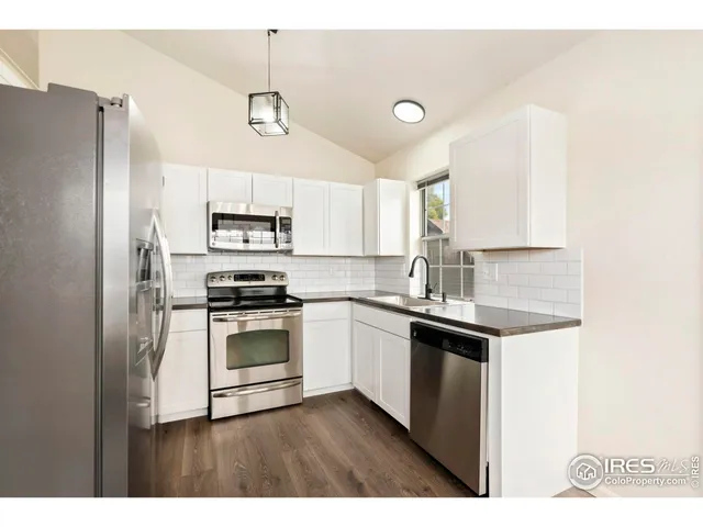 a kitchen with stainless steel appliances a stove a sink and white cabinets