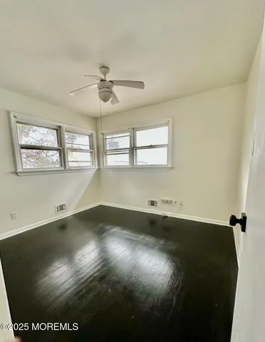 view of empty room with wooden floor and fan