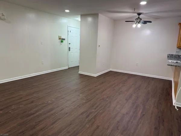 an empty room with wooden floor and a ceiling fan