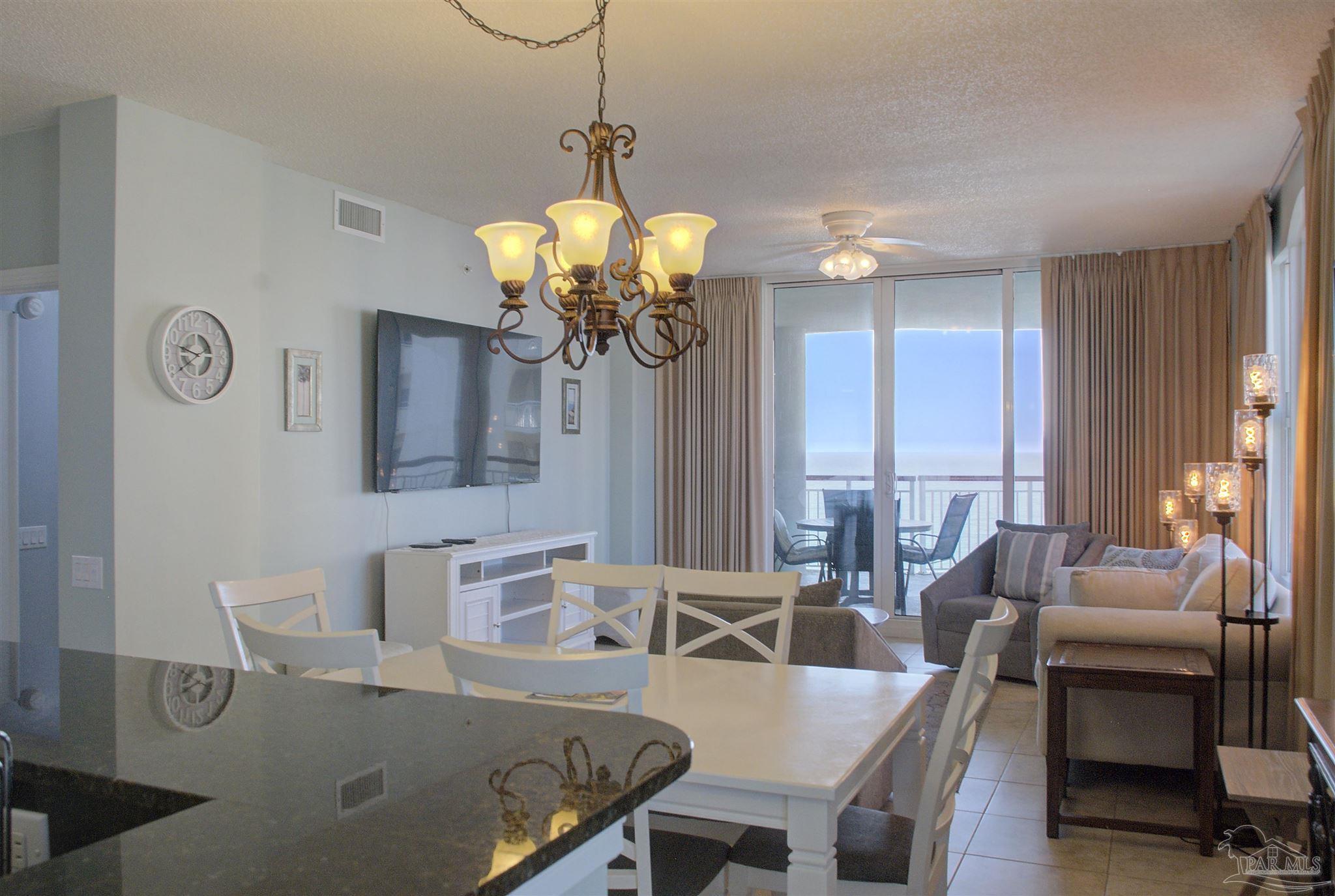 8501 Gulf Boulevard, Unit 10F Navarre, FL 32566 - Photo 12 of 35 a view of a dining room with furniture a chandelier and wooden floor
