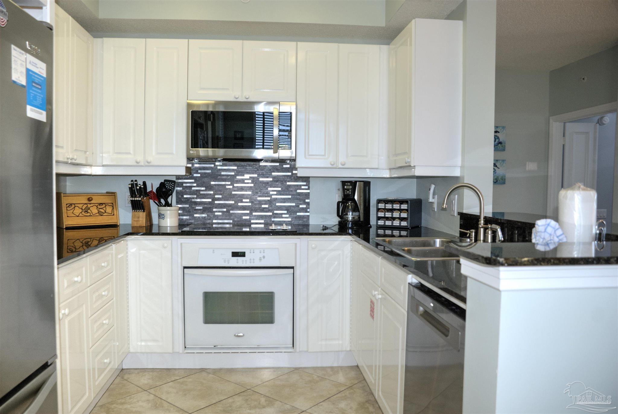8501 Gulf Boulevard, Unit 10F Navarre, FL 32566 - Photo 16 of 35 a kitchen with stainless steel appliances granite countertop a sink stove and microwave