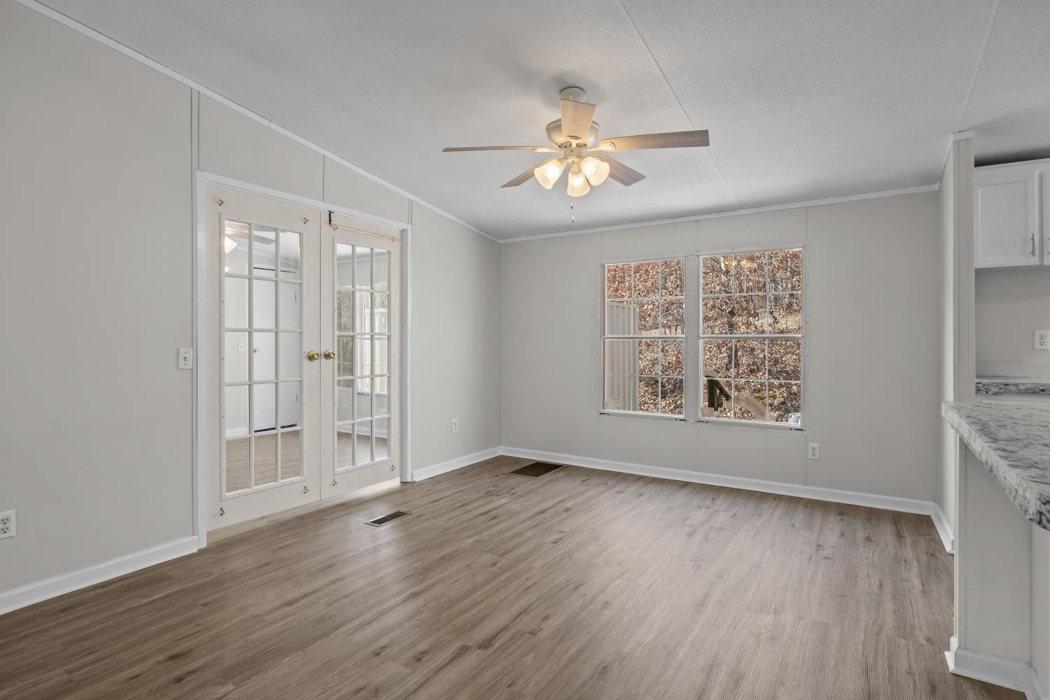 624 Nickletown Road Sugar Tree, TN 38380 - Photo 13 of 45 an empty room with wooden floor chandelier fan and windows