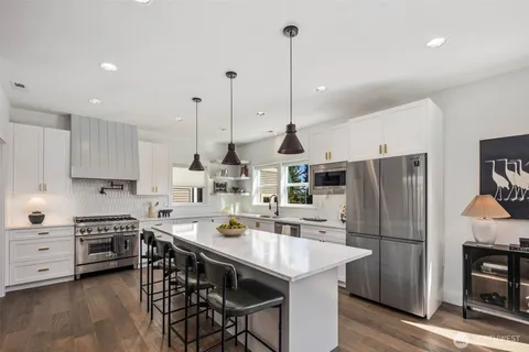a kitchen with stainless steel appliances a stove a sink a refrigerator a table and chairs