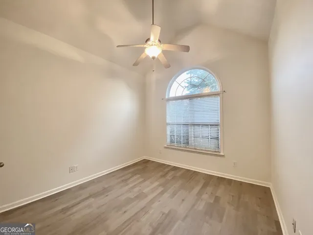 an empty room with a chandelier fan and windows