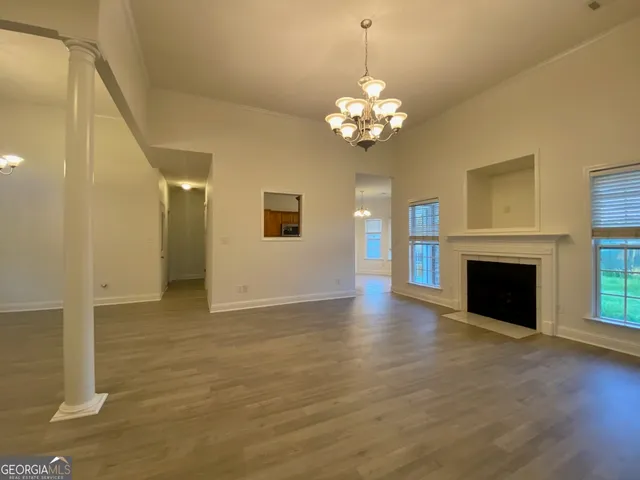 a view of a livingroom with a fireplace a chandelier and wooden floor