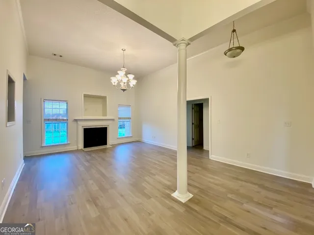 a view of an empty room with wooden floor and a fireplace