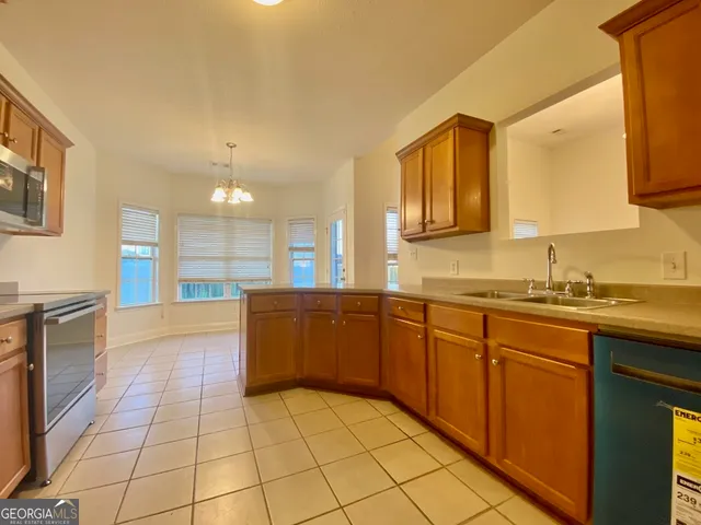 a large kitchen with granite countertop a sink and white cabinets