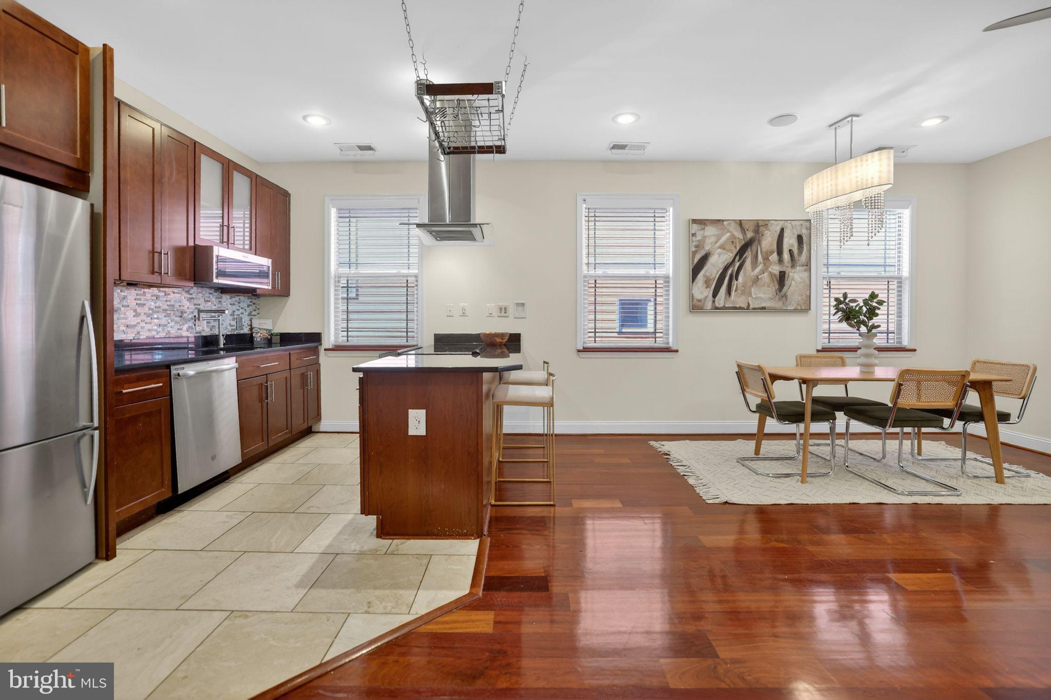 3573 Warder Street Northwest, Unit 7 Washington, DC 20010 - Photo 15 of 61 a kitchen with stainless steel appliances granite countertop a stove top oven a sink a dining table and chairs with wooden floor