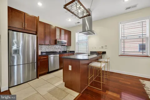 a kitchen with stainless steel appliances granite countertop a refrigerator a sink dishwasher a stove and a refrigerator with wooden floor
