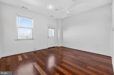a view of a livingroom with wooden floor and a bathroom