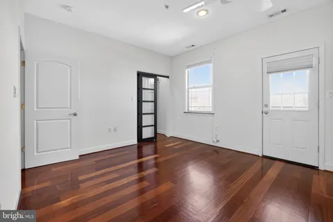 an empty room with wooden floor and windows