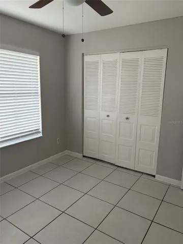 an empty room with a ceiling fan and window