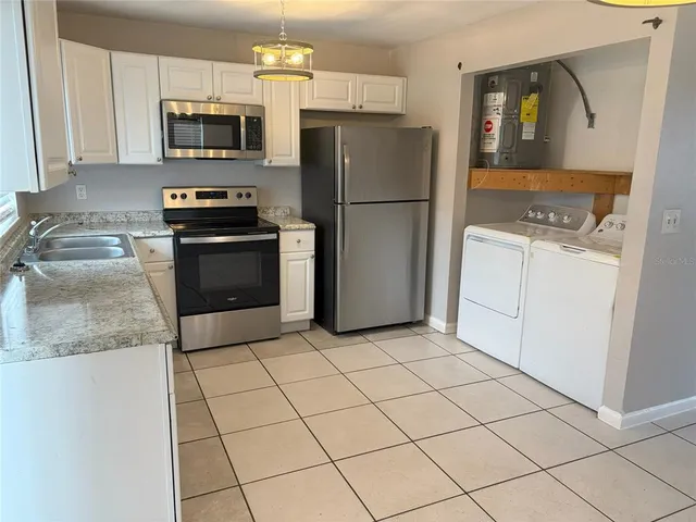 a kitchen with granite countertop a refrigerator and a stove top oven