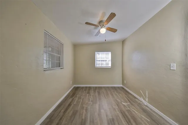 a view of empty room with wooden floor and fan