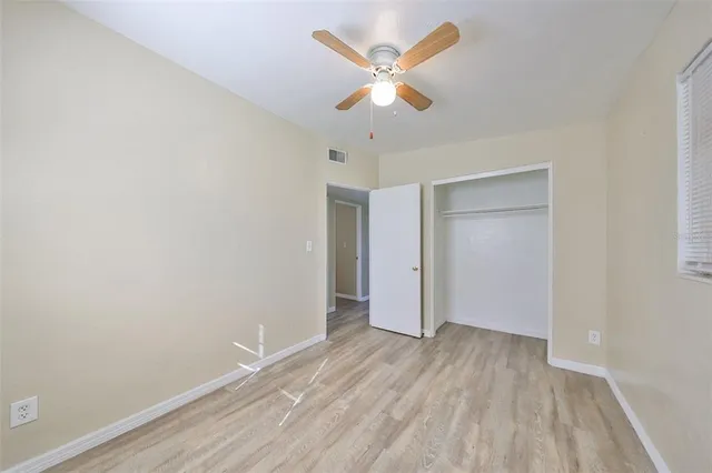 an empty room with wooden floor and a ceiling fan