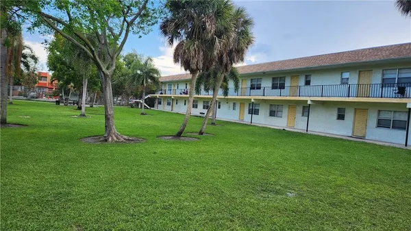 a view of an house with backyard and a tree