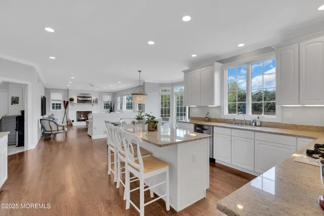 a kitchen with stainless steel appliances granite countertop a refrigerator a sink dishwasher and a dining table with wooden floor