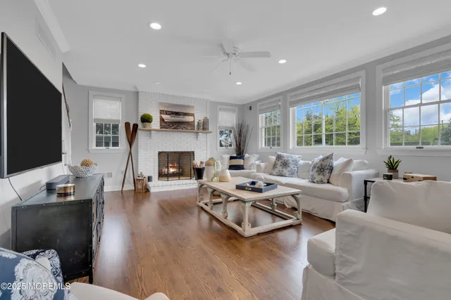a living room with furniture a fireplace a flat screen tv and a large window
