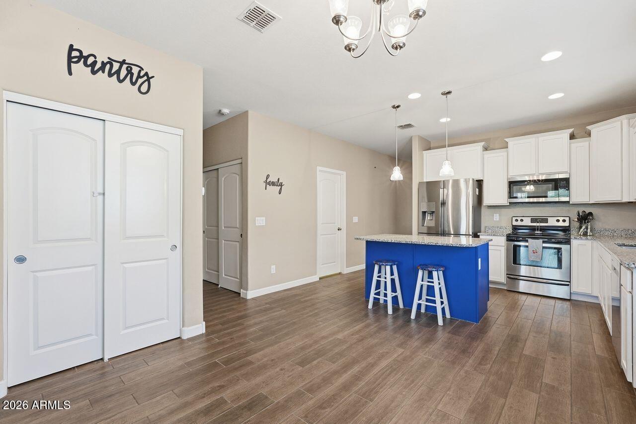 23602 West Ripple Road Buckeye, AZ 85326 - Photo 11 of 38 a open kitchen with stainless steel appliances granite countertop a refrigerator a stove top oven a sink dishwasher and white cabinets with wooden floor