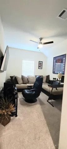 a living room with furniture gym equipment and a ceiling fan