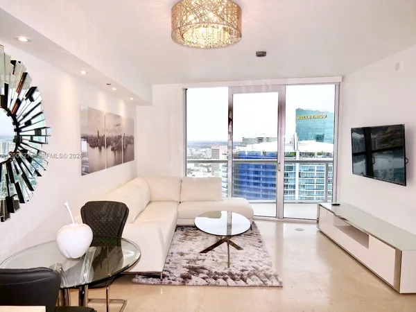 a living room with furniture a flat screen tv and a large window