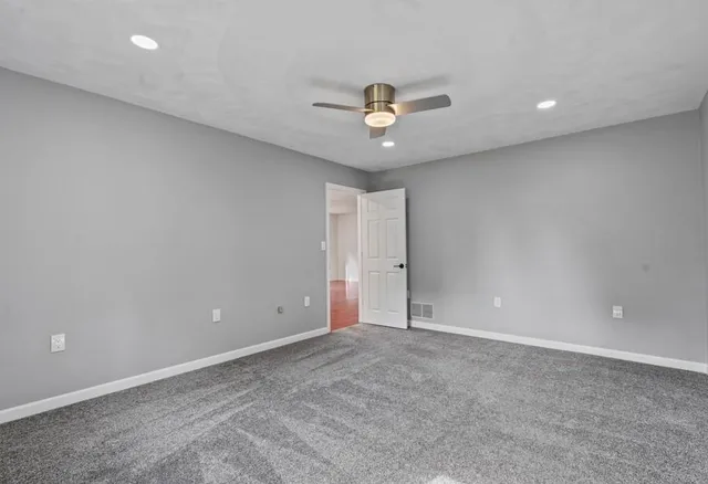 an empty room with a ceiling fan and wooden floor