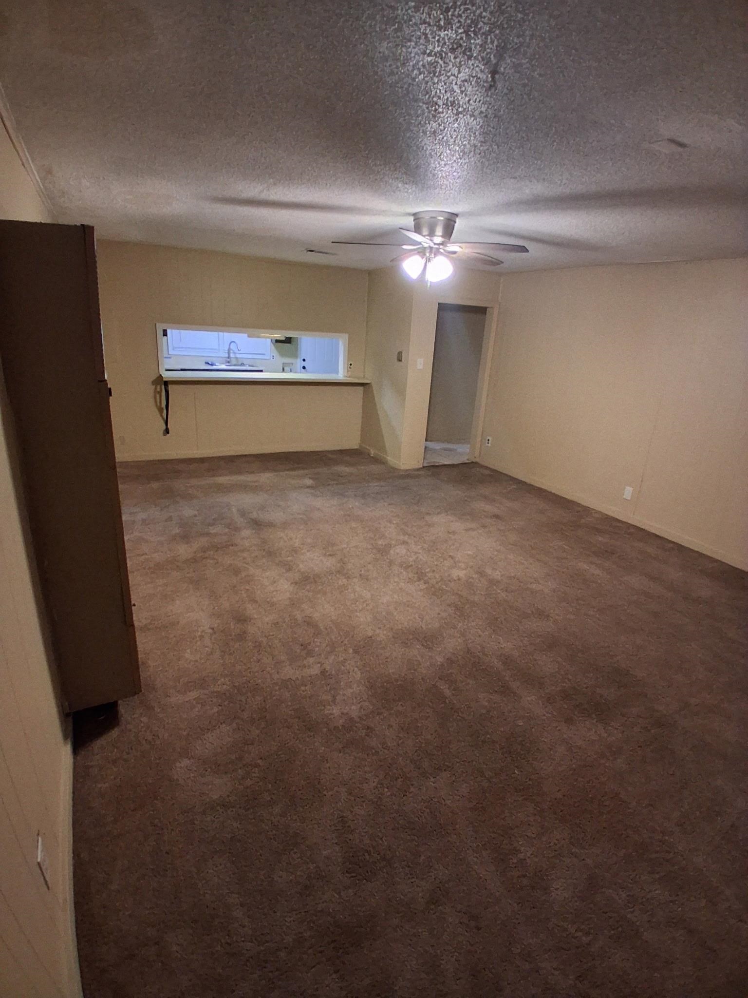 2435 Silver Street Memphis, TN 38106 - Photo 3 of 9 Empty room featuring dark carpet, a textured ceiling, and a ceiling fan