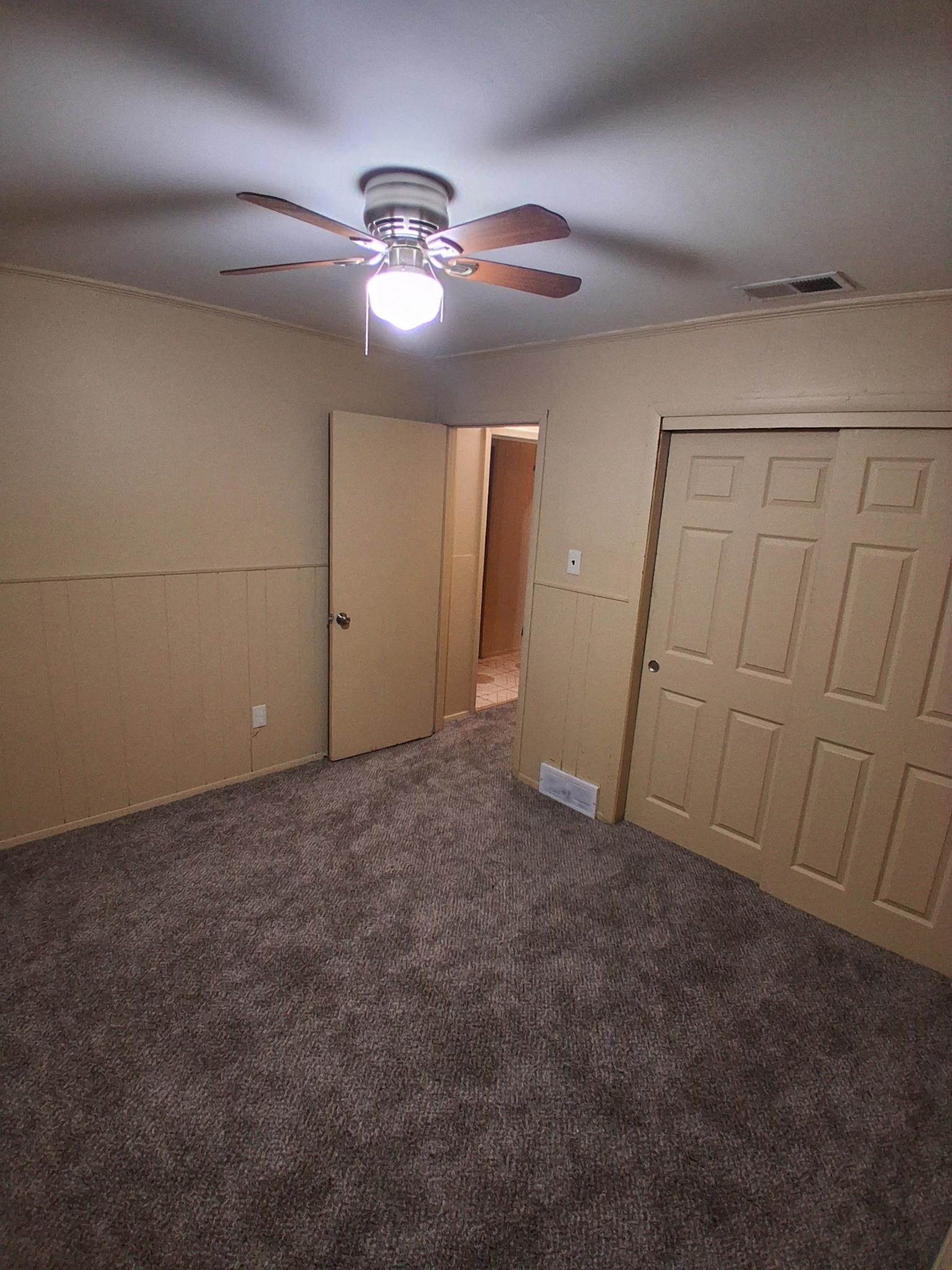 2435 Silver Street Memphis, TN 38106 - Photo 5 of 9 Unfurnished bedroom with a wainscoted wall, a closet, ceiling fan, and carpet floors
