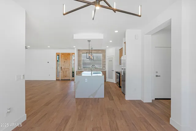 a view of an empty room and kitchen with ceiling fan