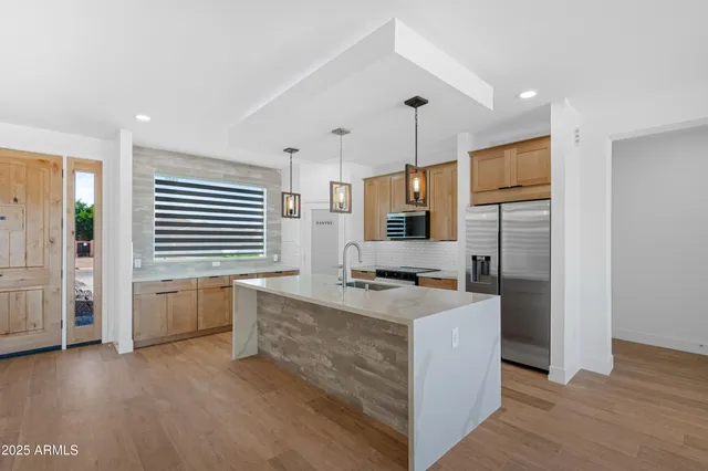 a kitchen with stainless steel appliances granite countertop a sink a stove and a wooden floor