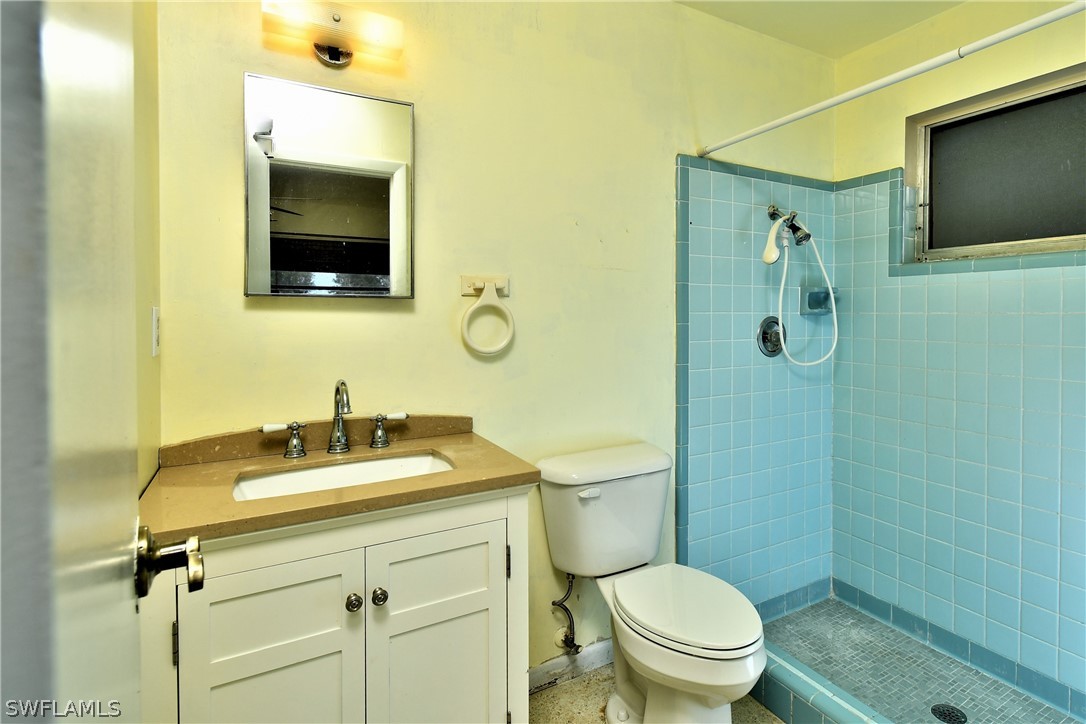 502 Wyoming Road Lehigh Acres, FL 33936 - Photo 13 of 20 a bathroom with a toilet sink vanity and mirror