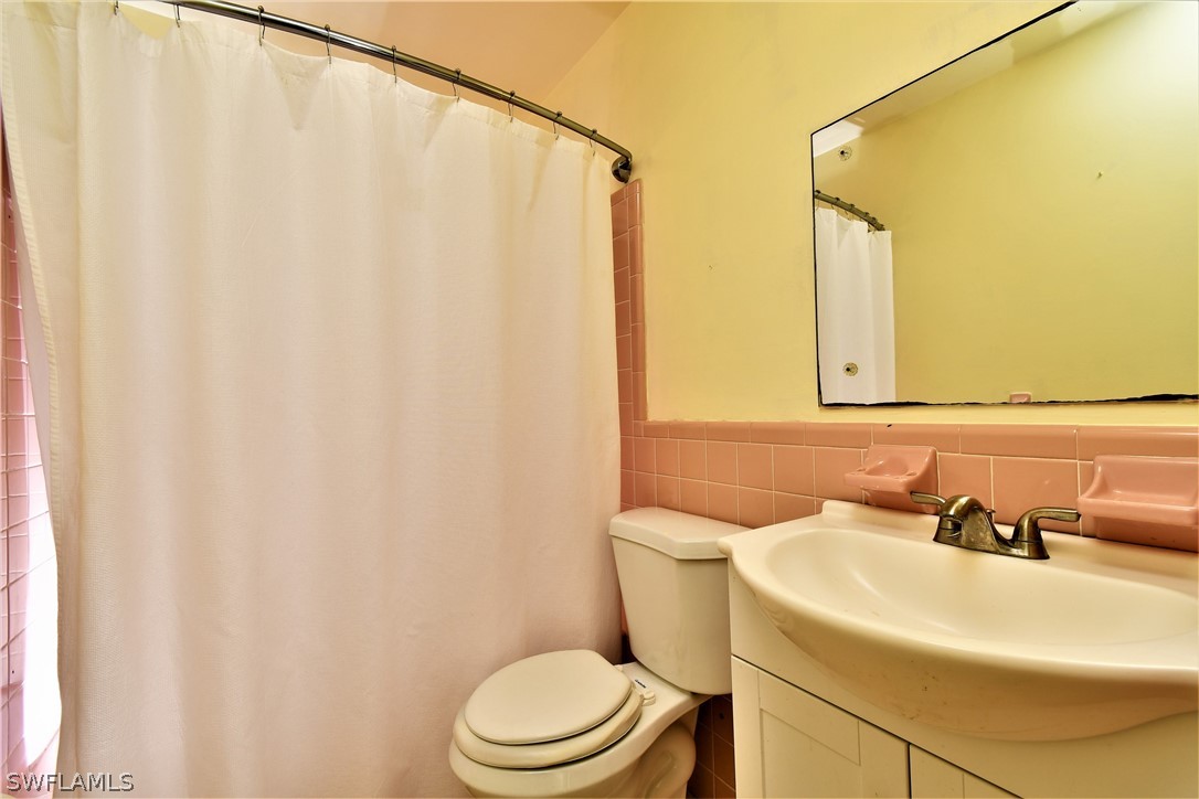 502 Wyoming Road Lehigh Acres, FL 33936 - Photo 16 of 20 a bathroom with a sink a toilet and shower curtain